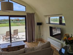 a living room with a couch and a table and windows at The Rookery in Greenfield Cross Roads