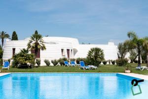 a swimming pool in front of a white house at Hotiday Gallipoli Masseria in Gallipoli