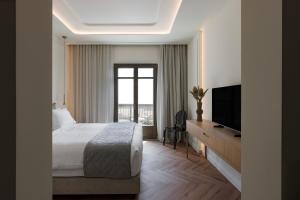 a bedroom with a bed and a flat screen tv at Heronia Suites in Karistos