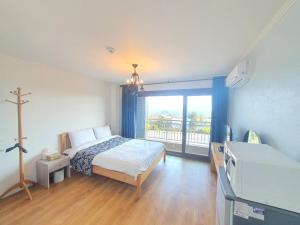 a bedroom with a bed and a large window at La Comma Pension in Seogwipo +28 photos