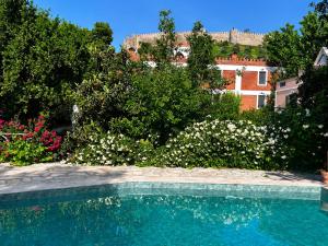 a swimming pool in a garden with flowers and a building at Hotel Kalehan in Selçuk