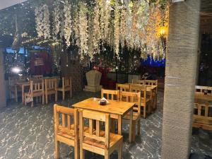 a restaurant with wooden tables and chairs and a chandelier at Aariv Inn BAGA BEACH in Baga
