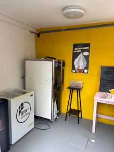 a room with a yellow wall with a refrigerator and a table at Bed and Stay Amsterdam in Amsterdam