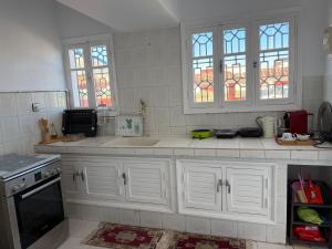 a kitchen with white cabinets and stained glass windows at Maison front de mer in El Jadida