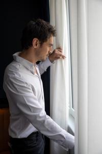 a man in a white shirt looking out of a window at 1.75 Paris Le Charme in Paris +47 photos