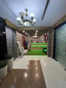 a living room with a chandelier and a green rug at Hotel Shifa Manor in Chāībāsa