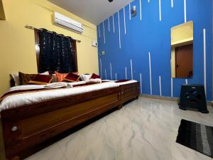ein Schlafzimmer mit einem Bett und einer blauen Wand in der Unterkunft Rivera inn in Tiruchirappalli
