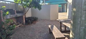 two wooden benches sitting on a brick patio at Sea Breeze Manor - Sage Unit in East London