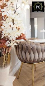 a vase with white flowers in it next to a chair at P6 Apartament Kaszmirowy in Pisz +5 photos