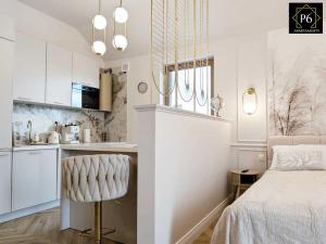 a white bedroom with a bed and a kitchen at P6 Apartament Kaszmirowy in Pisz