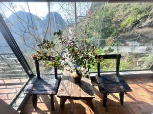 a wooden table with two chairs and a vase with plants at Villa Thẩm mã in Dồng Văn