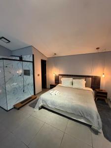 a bedroom with a large bed and a glass shower at Chalé Reserva El Paso in Mairiporã