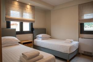 a bedroom with two beds and two windows at Evi Seaside Suites in Kanali