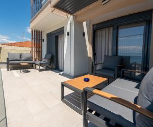 a balcony with couches and a table on a building at Evi Seaside Suites in Kanali