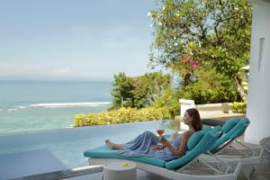 a woman sitting on a lounge chair with a glass of wine at Nusa Dua Cliff Ocean View with Private Beach in Nusa Dua +108 photos