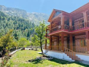 a large wooden house with a tree in front of it at Harshil View Home Stay in Harsil