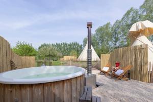 a hot tub in a backyard with a wooden fence at Tipi Marie at Logie Marie in Kaprijke