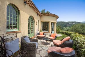 an outdoor patio with wicker chairs and a table at Les Pigerolles de Cabris in Cabris