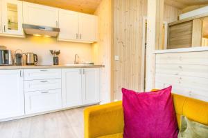 a living room with a yellow couch with a pink pillow at Naturverliebt am Diemelsee - Tiny House Wiesenblick in Heringhausen