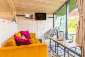 a living room with a yellow couch and a table at Naturverliebt am Diemelsee - Tiny House Wiesenblick in Heringhausen