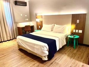 a hotel room with a large bed and a table at Oasis Plaza Hotel in Ribeirão Preto