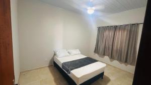 a small bed in a room with a window at Casa California - espaçosa in Formosa