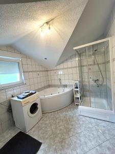 a bathroom with a tub and a washing machine at Kovač Home in Posušje