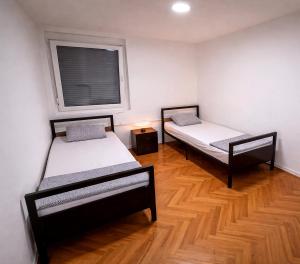 two beds in a room with a window at Apartman City With 3 Bedooms And Free Parking in Negotin