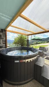 a hot tub on a patio with an umbrella at Le Repère De lAigle - Vue Panoramique in Cornimont