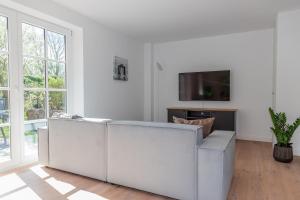 a white living room with a couch and a tv at Friesenfrühling in Borgsum