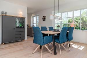 a dining room with a table and blue chairs at Friesenfrühling in Borgsum