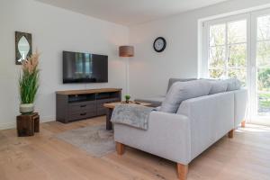 ein Wohnzimmer mit Sofa und Fernseher in der Unterkunft Sommergeest in Borgsum