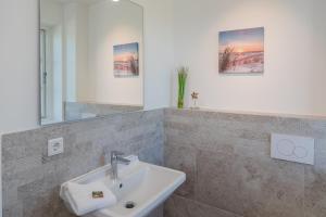 ein Badezimmer mit Waschbecken und Spiegel in der Unterkunft Sommergeest in Borgsum + 20 Fotos