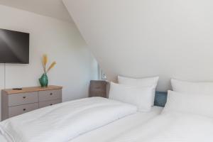 zwei Betten mit weißen Laken und ein Fernseher in einem Schlafzimmer in der Unterkunft Sommergeest in Borgsum