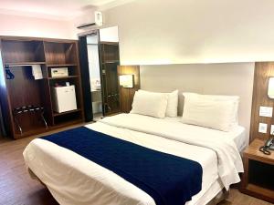 a bedroom with a large bed with a blue blanket at Oasis Plaza Hotel in Ribeirão Preto +44 photos
