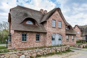 a large brick house with a thatched roof at Reetruhe in Borgsum