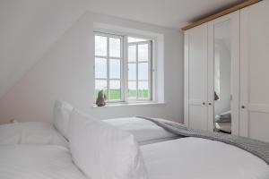 a white bedroom with a couch and a window at Wattenkieker in Borgsum