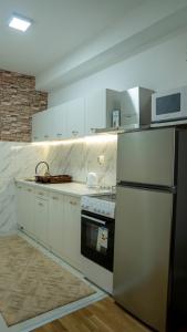 a kitchen with white cabinets and a stove and a refrigerator at Apartman M&Ð Foca-free parking garage in Foča