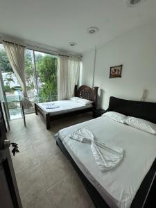 a bedroom with two beds and a large window at Hotel Cristalina in Melgar