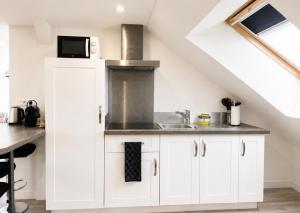 a kitchen with white cabinets and a sink at Studio spacieux et élégant au cœur de Bourbourg - gare à proximité in Bourbourg
