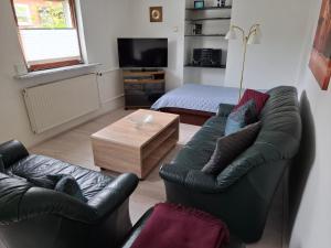 a living room with two leather chairs and a television at Ferienwohnung in Gartenlandschaft in Kassel
