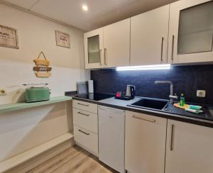 a kitchen with white cabinets and a sink at Coastline Apartments in Fuhlendorf +27 photos