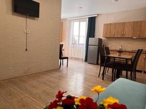 a living room with a kitchen and a table with flowers at Memory- borjomi in Borjomi