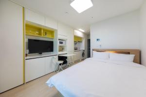 a white bedroom with a large bed and a desk at Yangyang Badastay in Yangyang