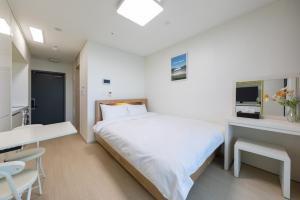 a bedroom with a large white bed and a desk at Yangyang Badastay in Yangyang