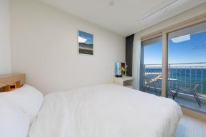 a bedroom with a white bed and a balcony at Yangyang Badastay in Yangyang