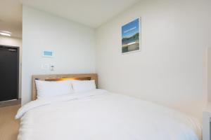 a bedroom with a white bed with a picture on the wall at Yangyang Badastay in Yangyang