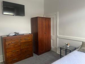 a bedroom with a wooden dresser and a bed at The Victoria Hotel in Collie