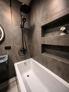 a bathroom with a white tub and a sink at Hostly, New Boulevard Prime Stay in Batumi +12 photos