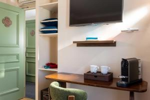 a room with a table and a television on a wall at Hotel Du Flaneur in Paris +36 photos